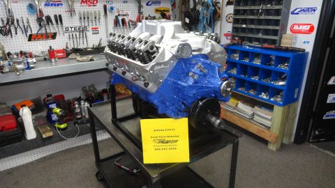 1982 Ford Bronco - Ford 427 engine on a stand in a workshop with tools and parts visible.