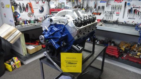 1982 Ford Bronco - A rebuilt Ford 427 V8 engine sits on a stand in a workshop, with tools organized on the wall in the background.