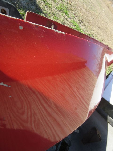 1976 Chevrolet Corvette - Red car fender showing wear and tear, with a portion of a white object visible on the right.