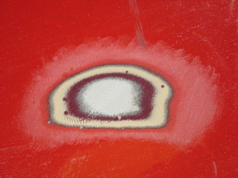 1976 Chevrolet Corvette - A close-up view of a sanded area on a red car's body, with the Supermotors logo visible in the lower right corner.