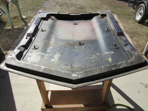 1976 Chevrolet Corvette - This is the underside of a car hood, resting on a wooden stand outdoors.