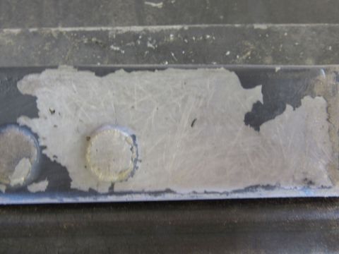 1976 Chevrolet Corvette - This image shows a close-up of a damaged metal component, peeling paint and visible rivets.