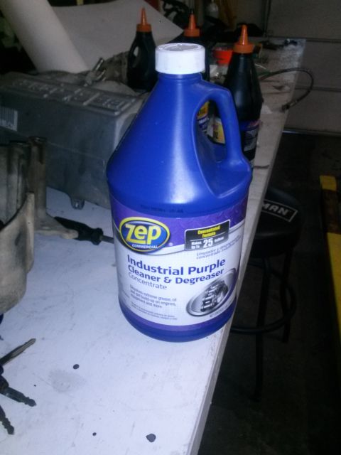 1996 Ford Bronco - A bottle of industrial cleaner sits on a workbench next to some engine parts.