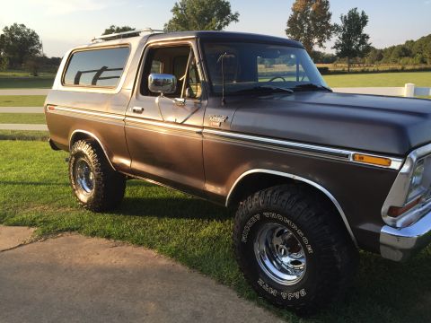 1978 Ford Bronco - This classic Ford Bronco is shown from a three-quarter front angle, parked on a grassy area with trees in the background.