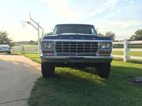 1978 Ford Bronco - Front view of a dark blue Ford truck with a prominent grille and chrome bumper parked on grass.