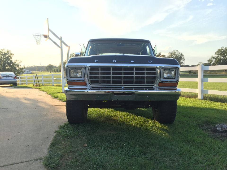 Dark blue Ford truck front view, grille with F-O-R-D lettering, chrome bumper, on grass next to driveway