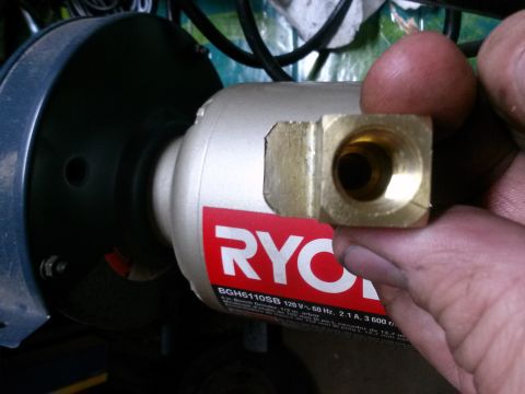 1996 Ford Bronco - A brass fitting is held up to a Ryobi bench grinder, showing a part for repair or modification.