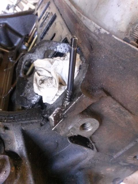 1996 Ford Bronco - A bolt is inserted into a metal engine part, with a rag nearby.