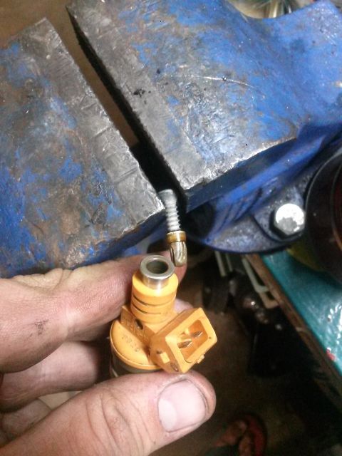 1996 Ford Bronco - A fuel injector is being worked on, held in a vise.