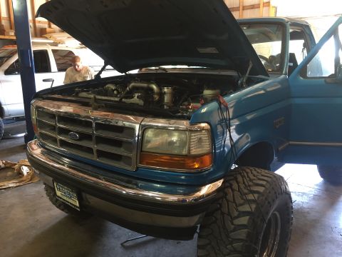 1995 Ford Bronco - A blue 1995 Ford Bronco is shown with its hood open, revealing the engine bay.