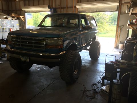 1995 Ford Bronco - This lifted 1995 Ford Bronco is parked in a garage with the doors open.