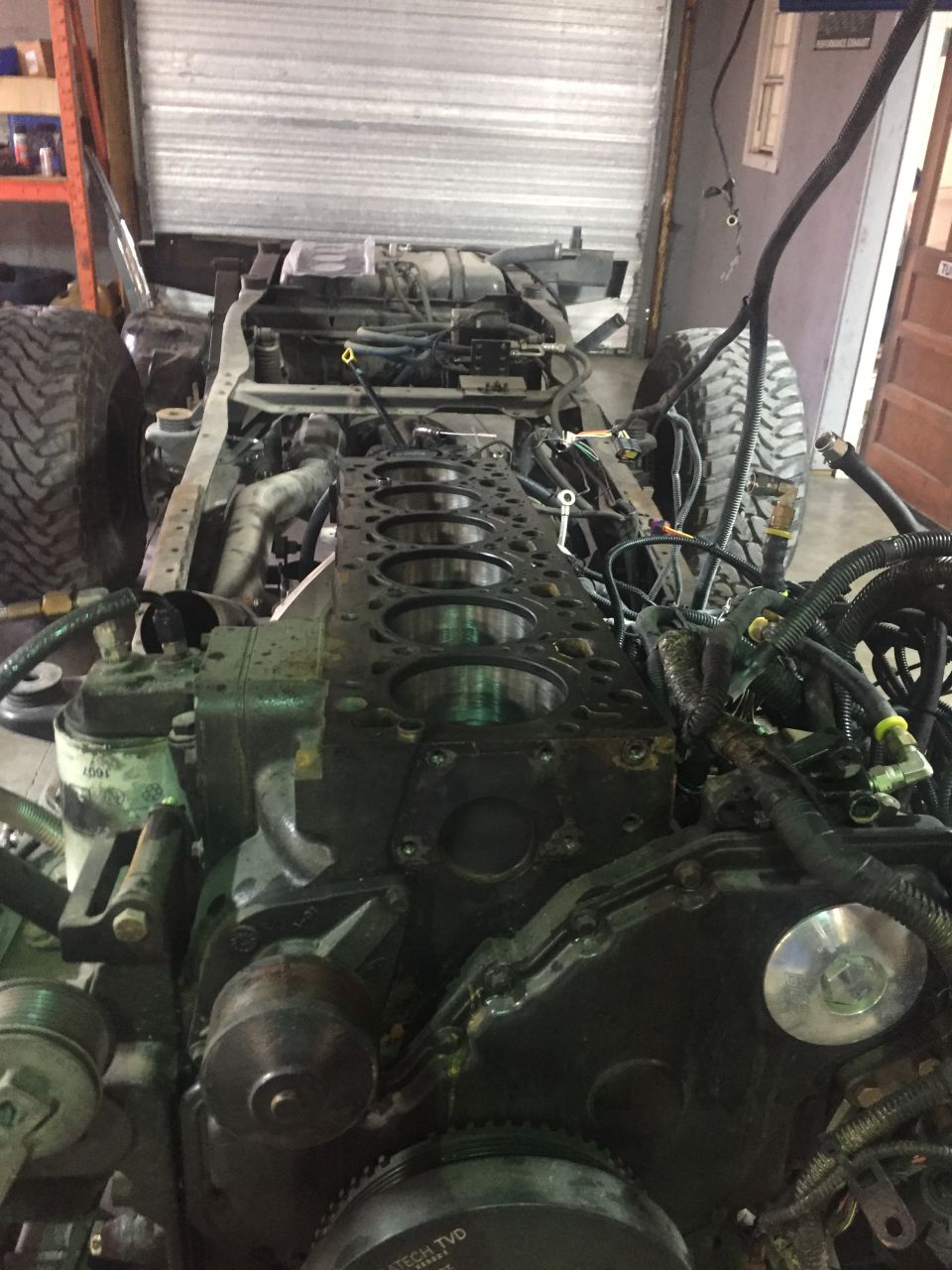 Engine block with cylinders exposed, chassis, and tires in a workshop