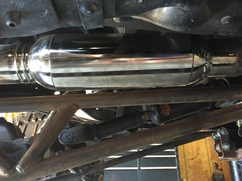 1995 Ford Bronco - The underside of a 1995 Ford Bronco shows a polished chrome exhaust system and a black muffler with orange lettering. Rusty metal tubing an…