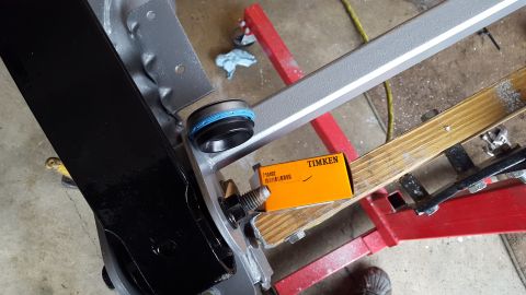 1994 Ford Bronco - A close-up view of a new Timken bearing and seal assembly, part number 710492, resting on a wooden support next to a painted black vehicle…