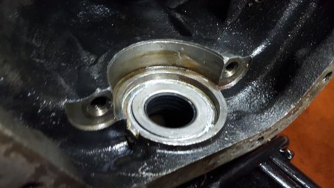 1994 Ford Bronco - A close-up view of a metal engine component, likely a bearing housing, with a seal visible inside. The part is dark and appears to be part…