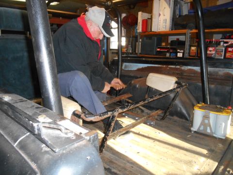 1972 Ford Bronco - An older man wearing a baseball cap and jacket works on the interior of a classic Ford Bronco. The vehicle's interior shows a metal roll ca…
