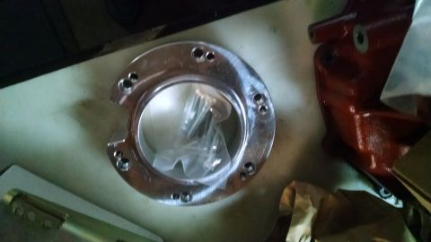 1985 Jeep CJ7 - A shiny, circular metal part with multiple bolt holes is shown. Inside the ring, a plastic bag contains several screws.