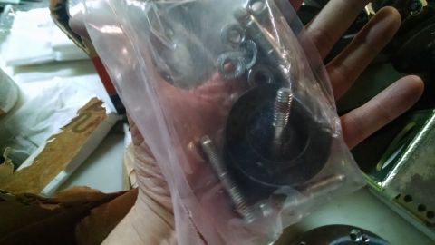 1985 Jeep CJ7 - A person's hand holds a clear plastic bag containing various metal hardware, including bolts, washers, and a rubber grommet with a threaded…