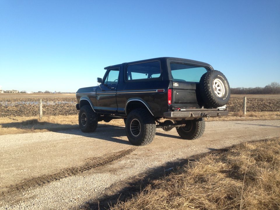 Black Ford Bronco parked on a gravel road with a spare tire on the back.