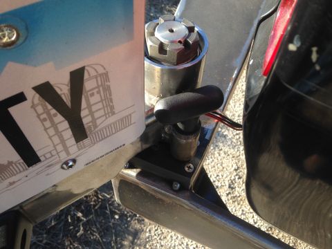 1979 Ford Bronco - A close-up view shows a license plate with the letters "TY" and a drawing of buildings, attached to a vehicle. A black lever with wires is…