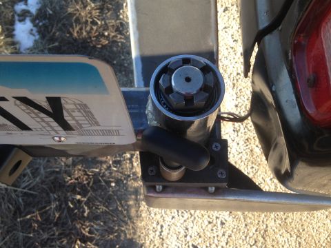 1979 Ford Bronco - A close-up view of a trailer hitch mechanism with a license plate attached. The hitch has a black lever and a silver locking mechanism with…
