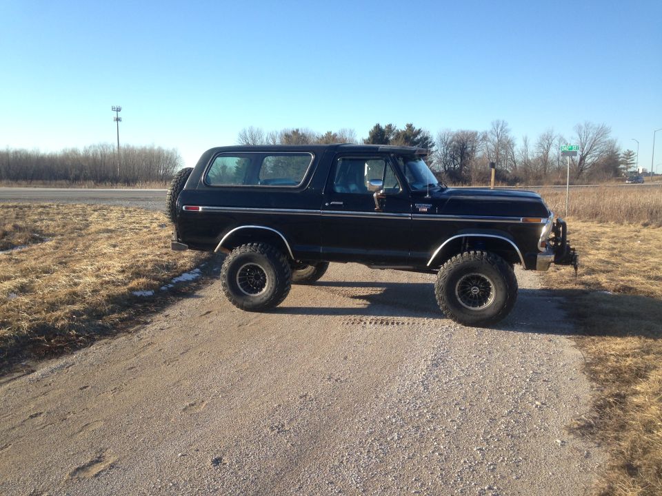 Lifted black 1979 Ford Bronco parked on gravel road.