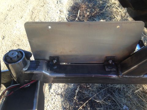 1979 Ford Bronco - A custom metal bracket is bolted to the frame of a vehicle, likely for mounting a license plate. The bracket is attached with two bolts and…