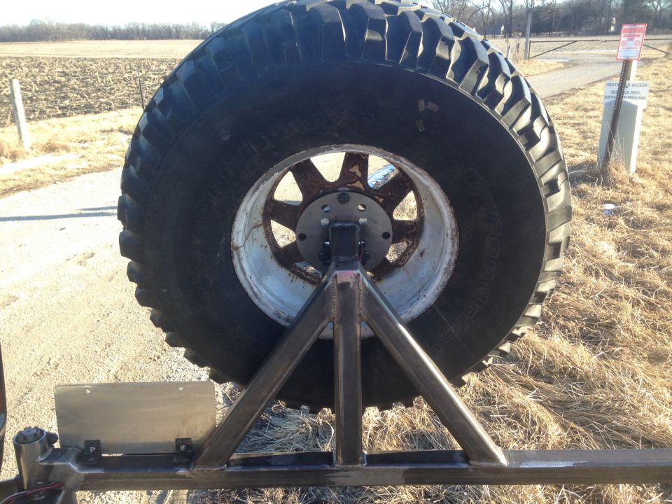 Rear view of a large off-road tire on a custom steel spare tire mount.