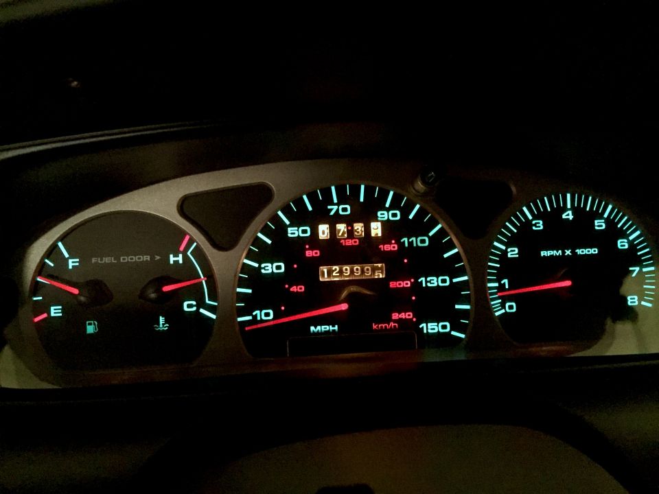 1999 Ford Taurus dashboard with lit gauges and odometer showing 129995 miles.