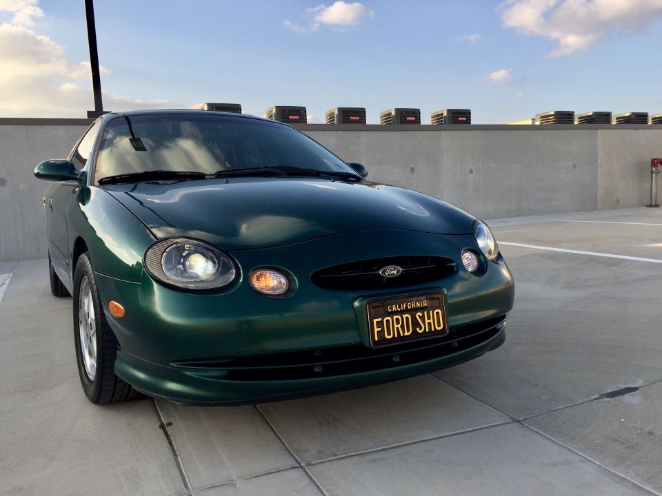 1999 Ford Taurus SHO in dark green, front 3/4 view, parked in a lot.