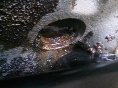 1996 Ford Bronco - A close-up view of a dark, oily, and corroded engine component, possibly a valve or piston head, with visible rust and debris.