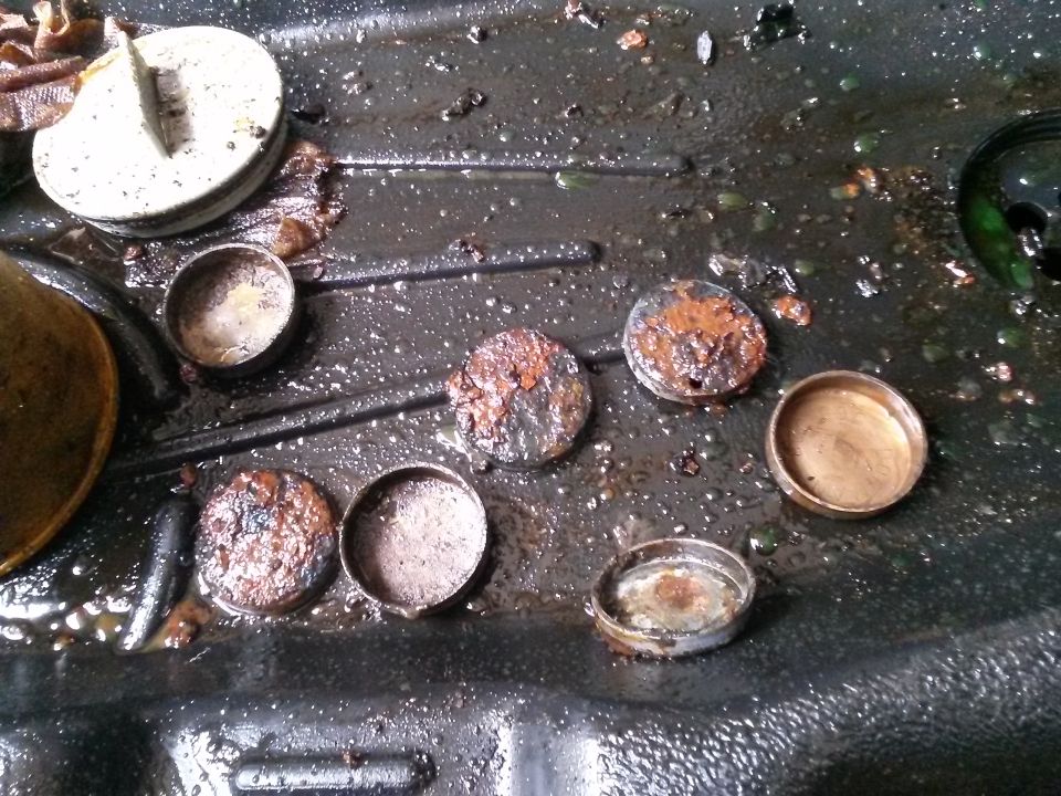 Rusty metal caps and a white cap on a dark, wet surface.
