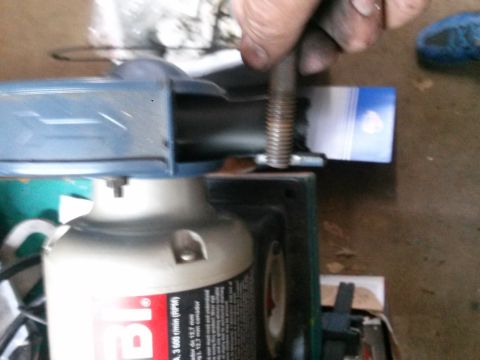 1996 Ford Bronco - A person's hand is holding a threaded bolt over a blue and white object. Part of a metal grinder is visible in the foreground.