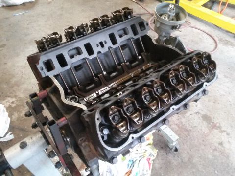 1996 Ford Bronco - A disassembled V8 engine block with cylinder heads and valve train components exposed is mounted on an engine stand. A distributor cap is v…