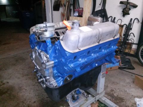 1996 Ford Bronco - A blue V8 engine block with silver valve covers sits on an engine stand in a garage. The engine has a distributor cap and an orange rag sti…