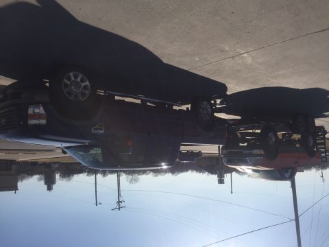 1982 Ford Bronco - A dark blue Ford F-Series truck is parked on asphalt, towing a red trailer with a boat. The truck is viewed from the front-side angle, with…