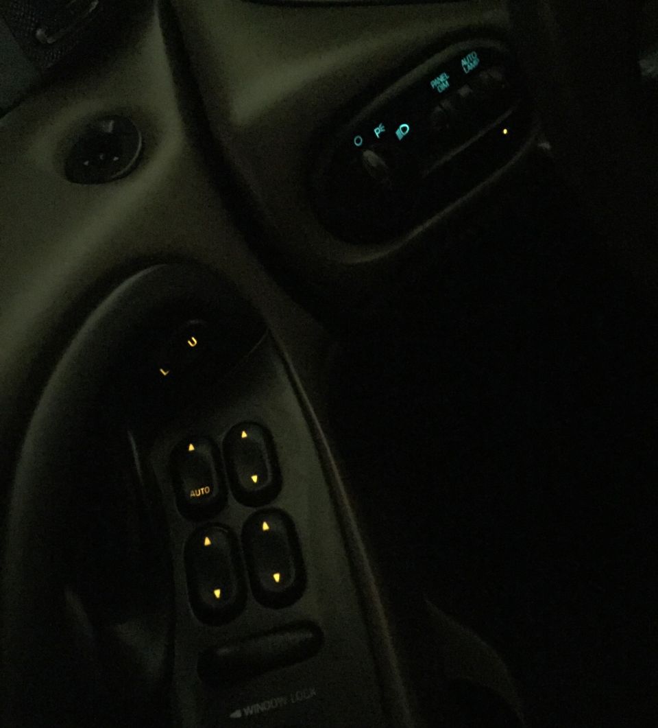 Car interior: power window controls and dashboard light controls.