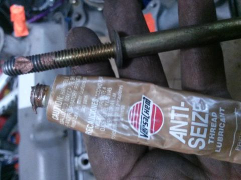 1996 Ford Bronco - A hand is holding a bolt that has been coated with anti-seize compound, and a tube of Versachem Anti-Seize Thread Lubricant is also visible.