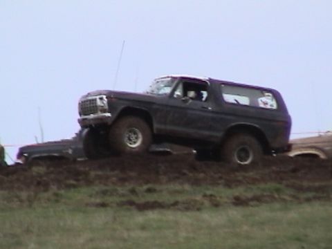 1994 Ford Explorer - A dark SUV with a white roof navigates a muddy terrain during an event.