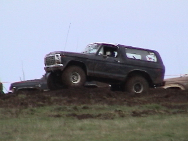 Dark SUV with white roof, lifted suspension, off-road tires, stuck in mud