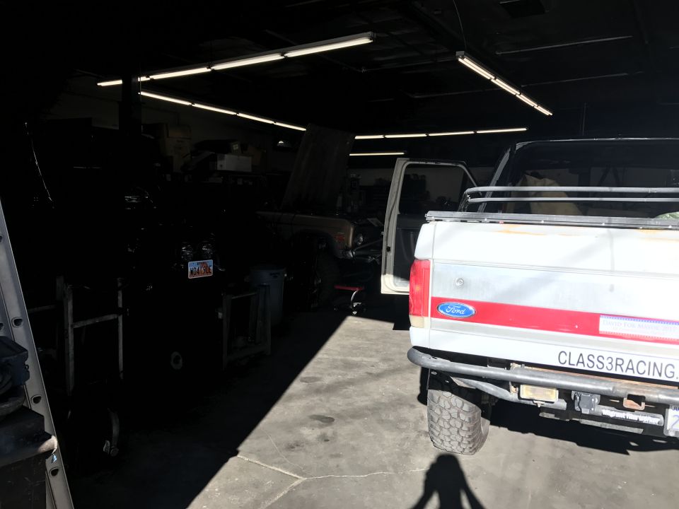 Shop interior with a white Ford pickup parked beside workbenches and equipment