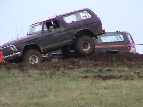 1994 Ford Explorer - This dark SUV, likely a 1978 model based on its grille, navigates a challenging muddy terrain alongside another vehicle.