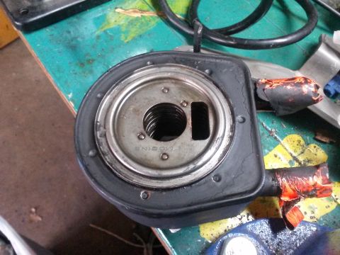 1996 Ford Bronco - A close-up, overhead view of a Modine oil cooler adapter with a black rubber gasket and a threaded metal center. The adapter appears to be…