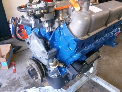 1996 Ford Bronco - A blue painted Ford V8 engine block is mounted on an engine stand in a garage setting. Visible parts include the valve covers, intake manif…