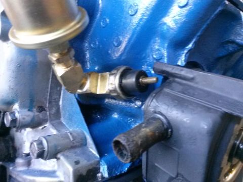 1996 Ford Bronco - A close-up view of an engine block with various brass and black fittings attached. The engine block is painted a vibrant blue.