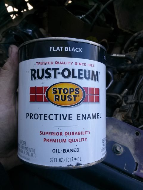 1996 Ford Bronco - A hand holds a can of Rust-Oleum Flat Black Protective Enamel paint. The can is white with red and black lettering and features the Rust-Ol…