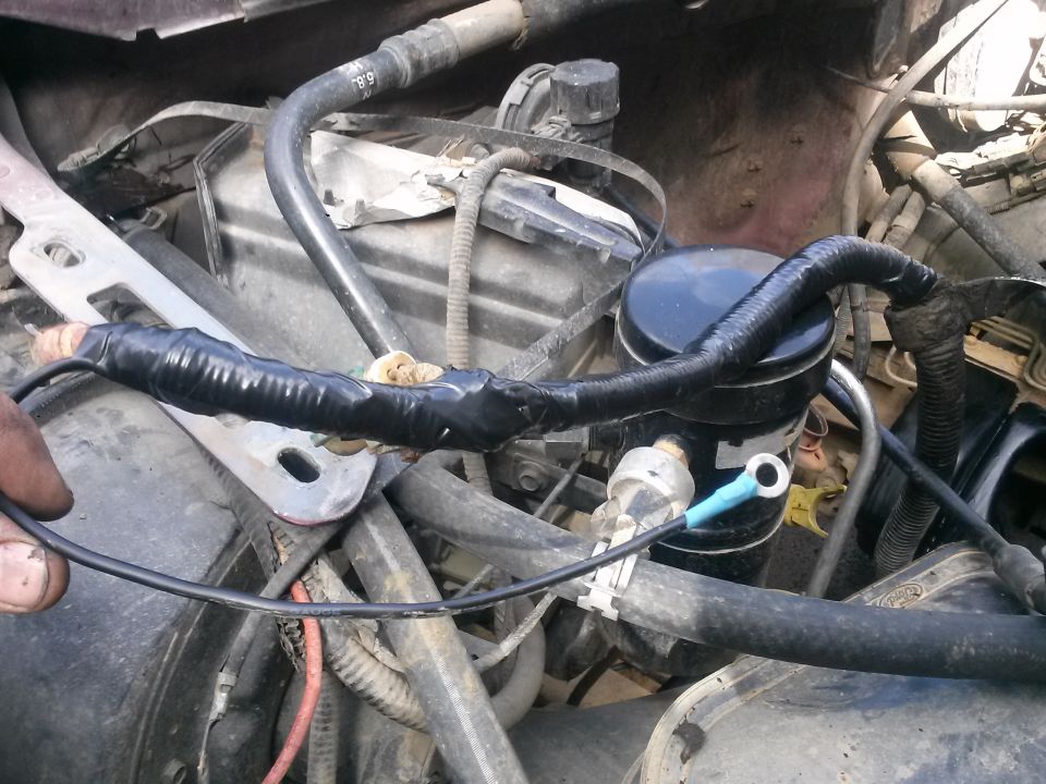 Close-up of engine wiring with black tape and a blue ring terminal.