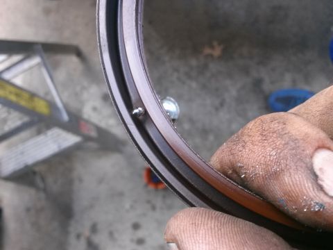 1996 Ford Bronco - A close-up shot shows a hand holding a dark-colored gasket with a small metal fastener protruding from it. The gasket appears to be a compo…