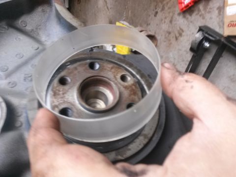1996 Ford Bronco - A hand holds a clear plastic ring over a metal pulley assembly with bolts. The pulley appears to be part of a vehicle's engine or drivetrai…