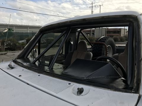 1990 Ford Bronco - Photo of a pickup truck cab fitted with a roll cage and racing seats, not a technical document.